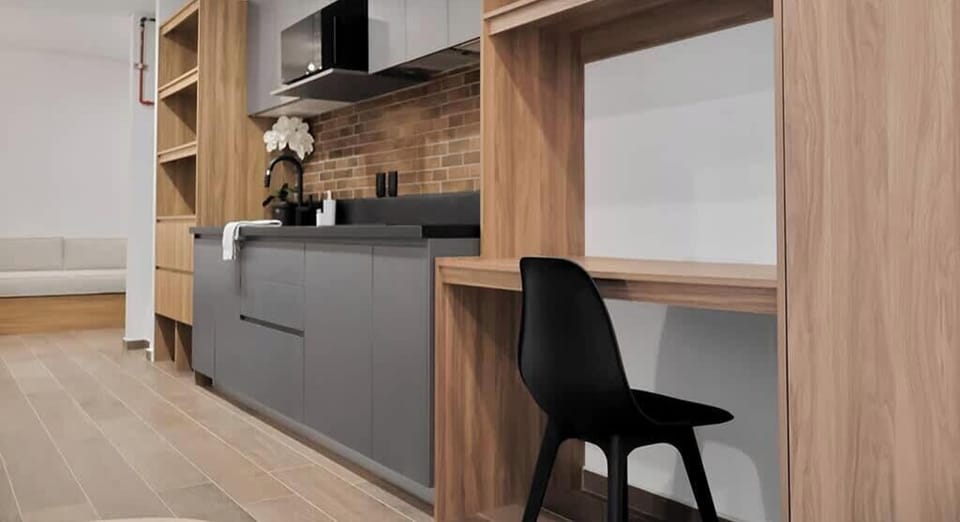 Sleek kitchen w/ wood cabinetry, dark counters & bar seating for casual meals