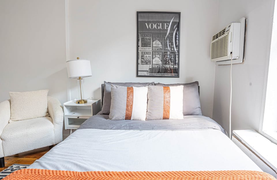 Modern bed with chic decor, armchair, and AC comfort