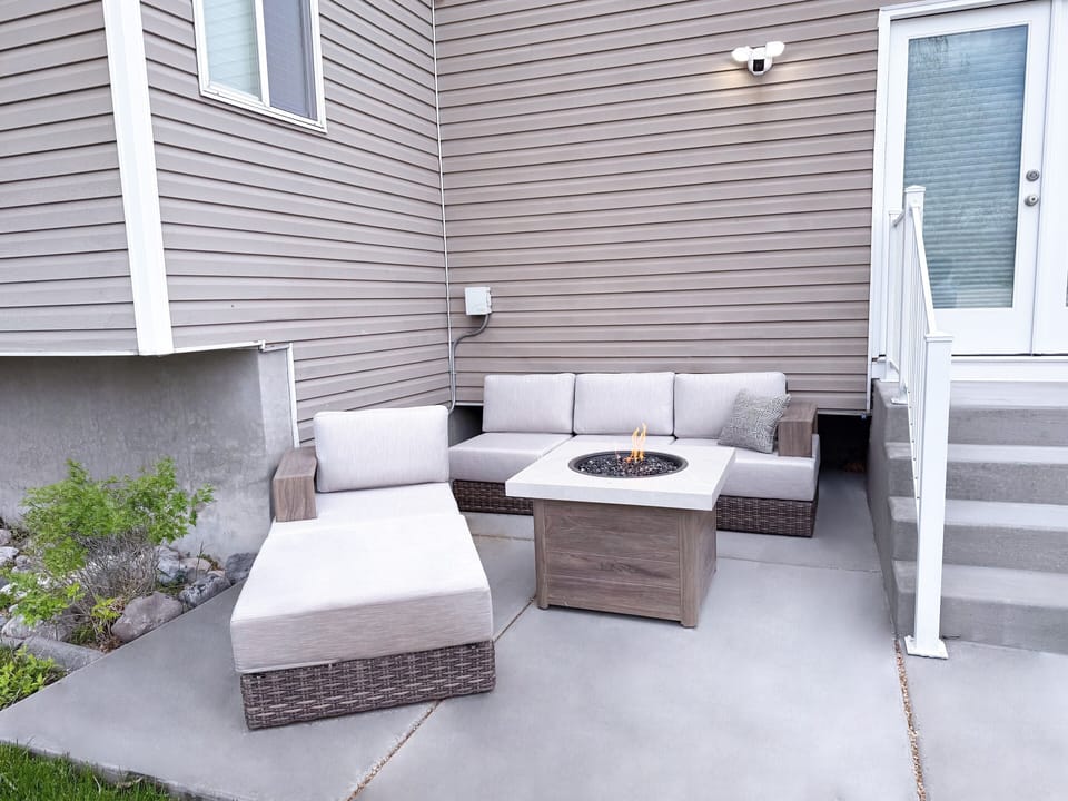 Outside fire pit, couch and comfortable lounge chair.