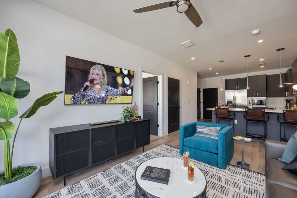 Unit 3: Welcome to a bright and open concept living room that exudes modern elegance. Designer furnishings enhance the sophistication of the space, while a smart TV provides entertainment options and a pull-out couch.