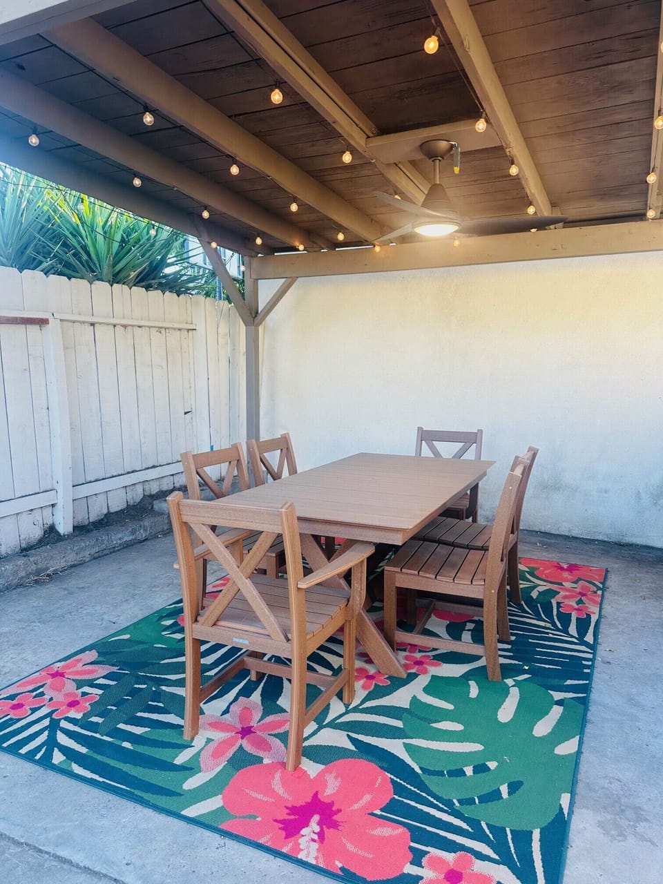 Outdoor dining table under a fan with twinkle lights for dining al fresco 
