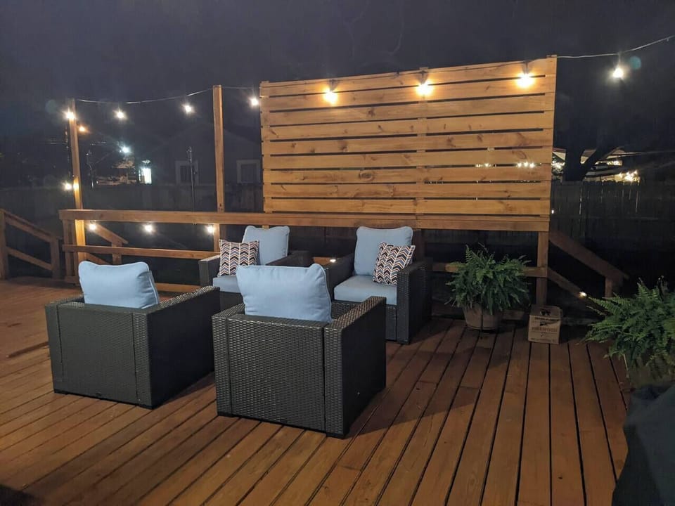 Expansive outdoor entertaining deck with gas grill, multiple seating areas, and string lights for family gatherings in downtown Pensacola.