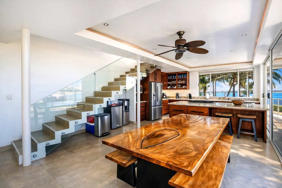 Spacious Open Kitchen & Dining Area with Custom Wood Table, Breakfast Bar & Modern Coastal Design