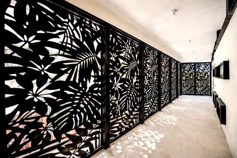 Stylish Hallway with Decorative Tropical Privacy Screens, Modern Architectural Details & Natural Light Patterns Creating a Unique Coastal Design Atmosphere