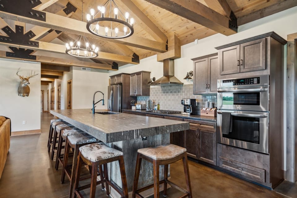 Open-concept kitchen featuring seating for a crowd, statement lighting, and seamless flow into the living and game areas.
