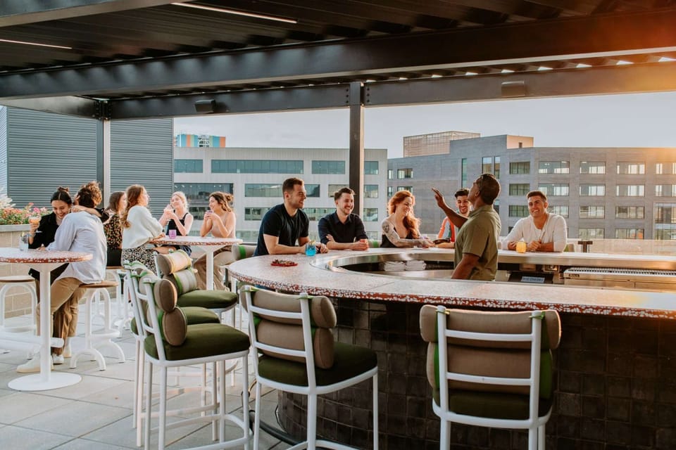 Guests enjoying drinks at a rooftop bar with city backdrop