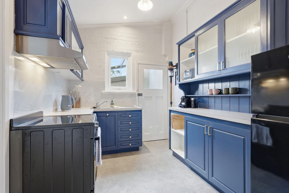 Cook with ease in the beautifully updated kitchen, featuring signature navy cabinetry, full-sized appliances and thoughtful essentials.