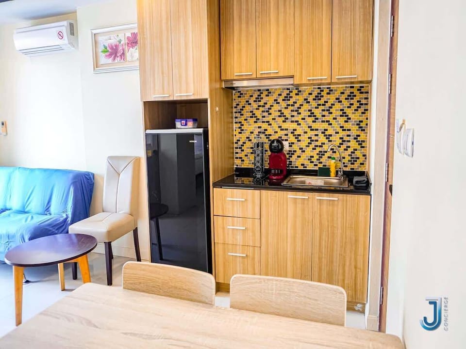 Petite cuisine fonctionnelle au look moderne, équipée de tout le nécessaire : frigo, évier, machine à café, rangements malins et dosseret coloré qui réveille le tout.