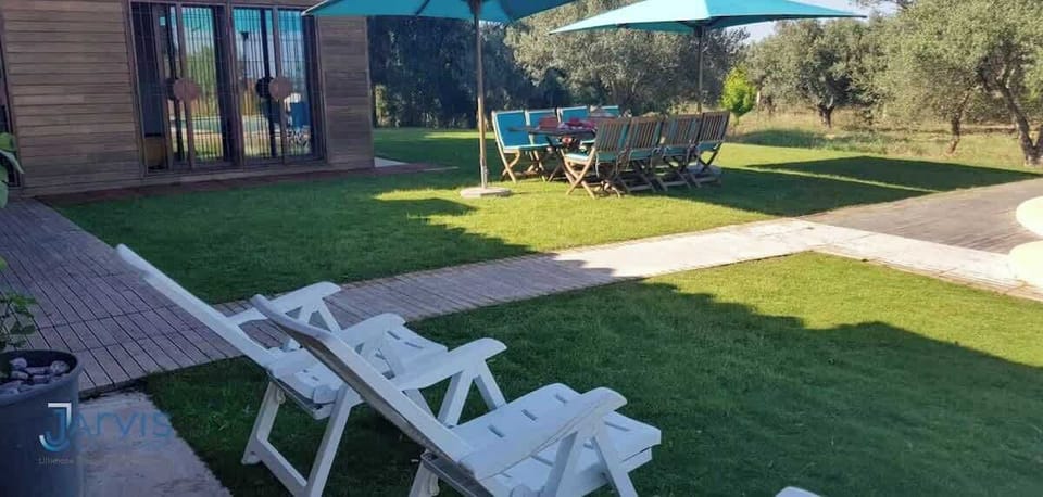 Espace détente avec chaises longues et coin repas ombragé. Une belle invitation à vivre dehors, dans un jardin à la fois vaste, vivant et reposant.