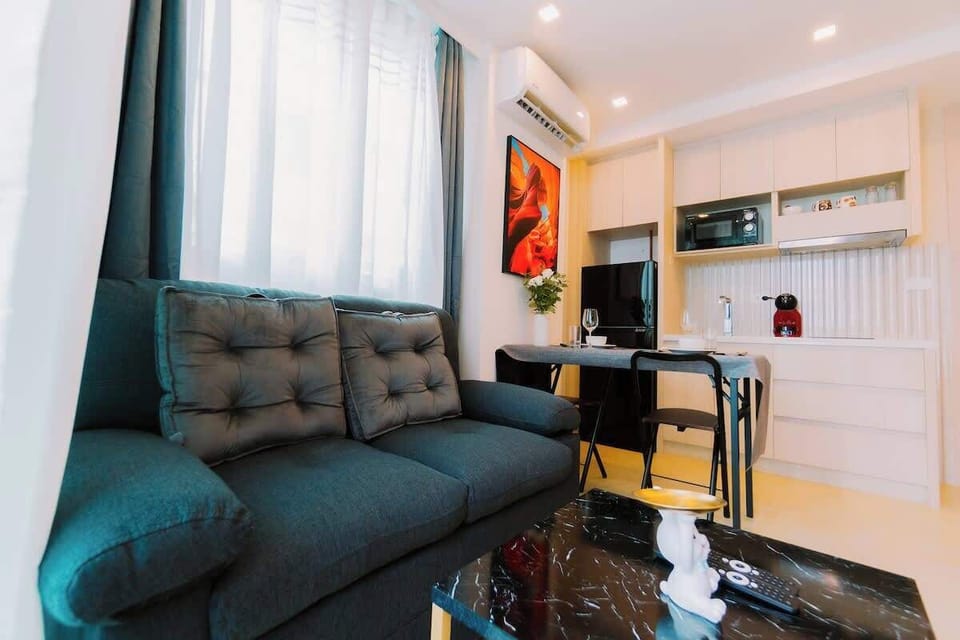 Salon à deux pas de la cuisine entièrement équipée en arrière-plan. Un espace lumineux et bien aménagé pour des moments de détente ou des repas conviviaux. Parfait pour un séjour alliant style et praticité.