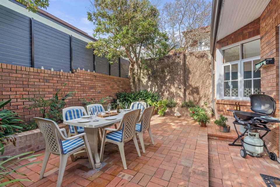 A relaxing backyard with a table, four chairs and lush plants creating a tranquil setting.