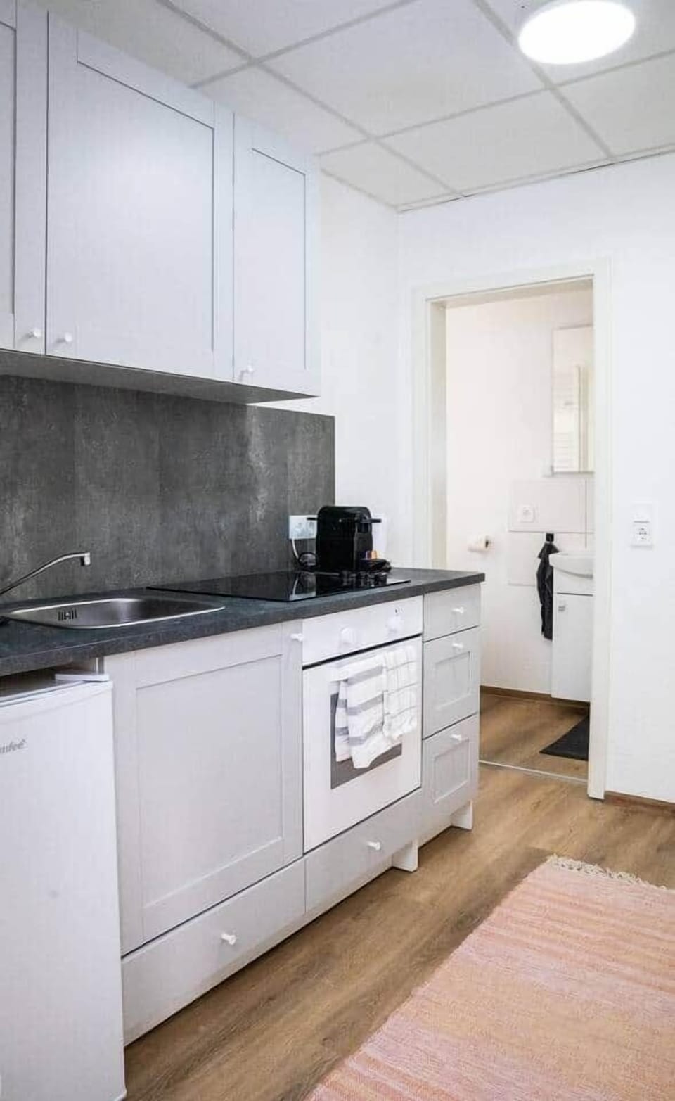 Küche mit Backofen, Ceranfeld, Kaffeemaschine, Wasserkocher und Kühlschrank