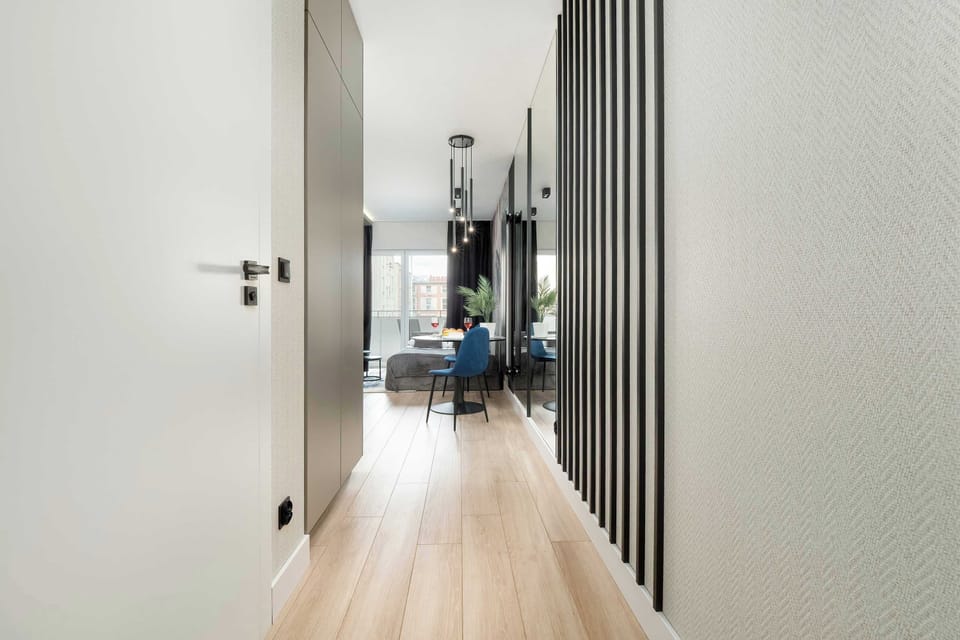 A bright corridor with wooden flooring, leading to various rooms within the apartment.

