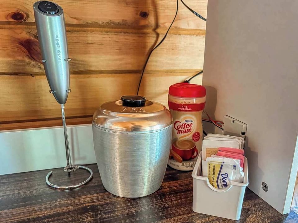 A charming setup featuring a tea container, sugar, creamer, and a milk frother—everything you need for a cozy, café-style beverage experience during your stay.