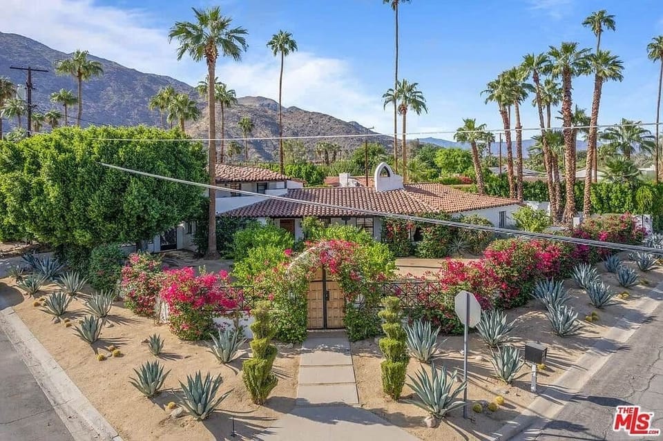 Iconic Spanish villa with mountain views, lush hedges, and desert blooms.