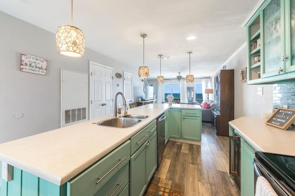 Cook your favorite meals in this spacious kitchen featuring mint green cabinets, elegant pendant lighting, and modern appliances.