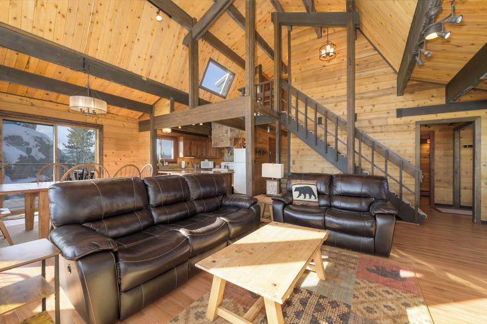 Sink into plush leather sofas beneath soaring wood beams, where rustic charm meets modern comfort in your mountain retreat.