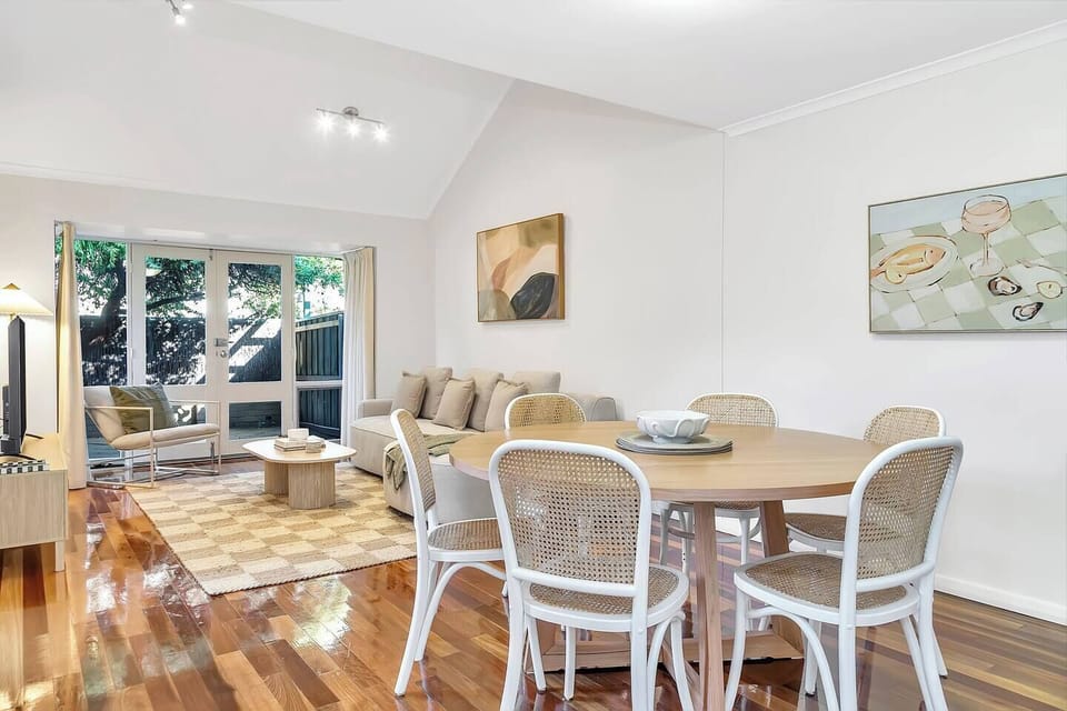 Gather around the timber dining table, surrounded by six rattan chairs, for relaxed meals and effortless conversation.