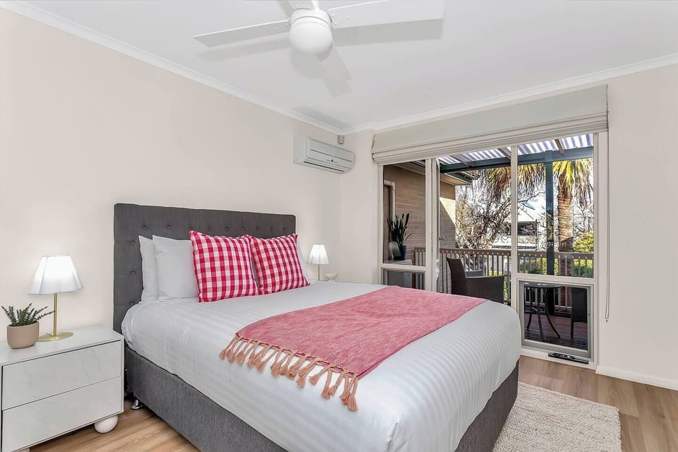 Located on the upper floor, the primary bedroom features a queen bed, direct access to a private balcony, a built-in wardrobe, and split-system climate control for year-round comfort.