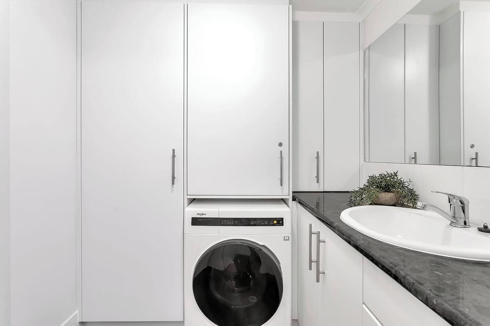 Conveniently located on the ground floor, the laundry area features a washer-dryer, large sink and ample storage cabinetry, with a second toilet and separate vanity located close by.