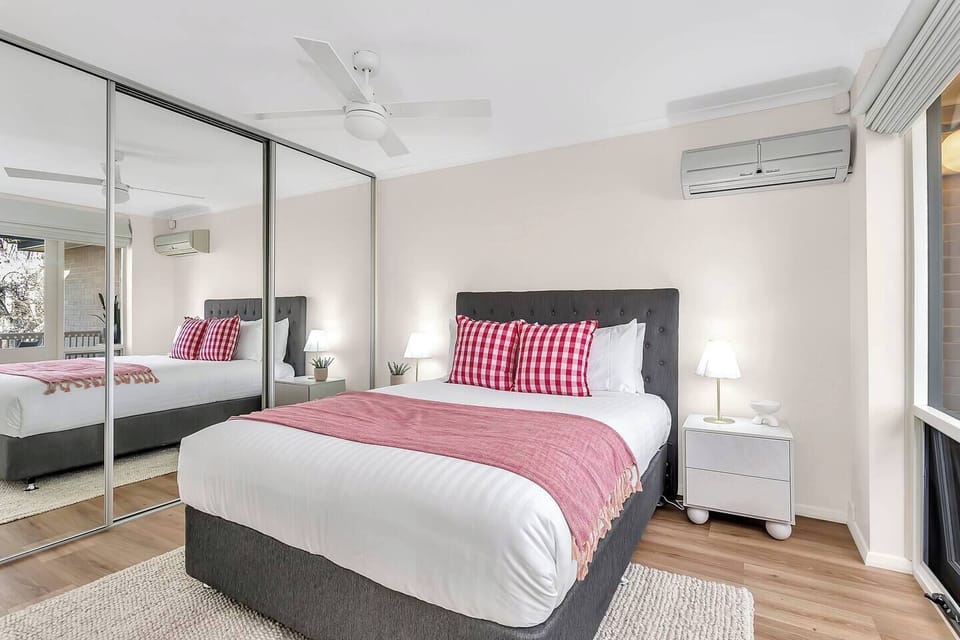 The primary bedroom features a mirrored wardrobe for generous storage, with soft lighting and a ceiling fan creating a restful, calming atmosphere.