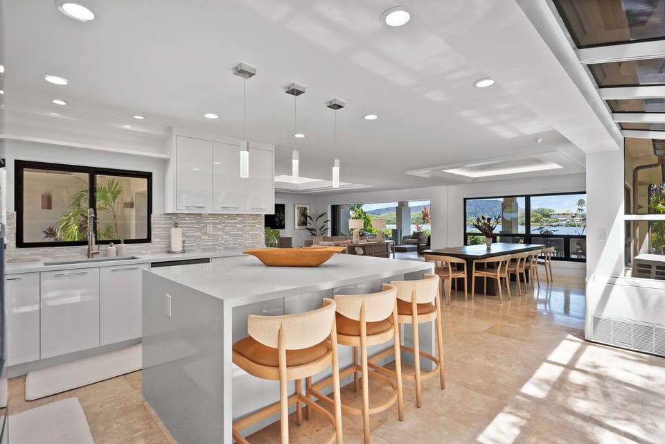 Sleek chef’s kitchen with island seating and open flow to dining and outdoor living spaces.