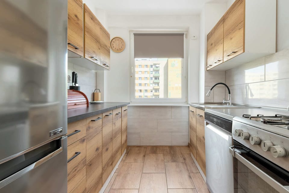 A longer kitchen view showing a compact layout with modern appliances, wooden cabinets, and ample lighting.
