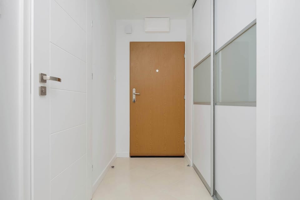 The spacious, bright hallway with a large mirror and wooden accents welcomes guests with a warm, modern feel.