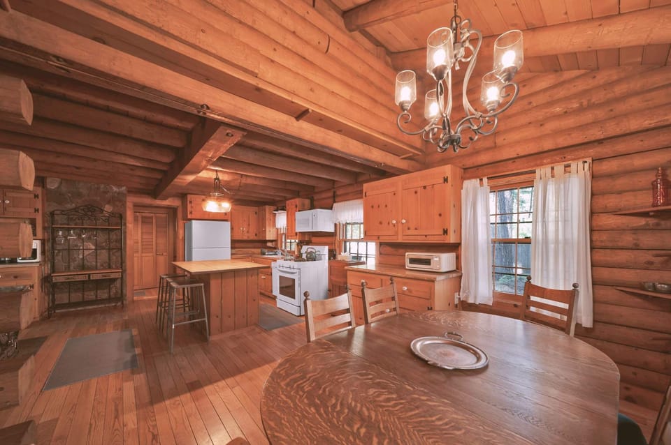 Step into a beautifully preserved log cabin kitchen and dining space that radiates warmth, charm, and functionality. With its classic wood-planked ceilings, exposed beams, and pine cabinetry, this space captures the essence of mountain living.