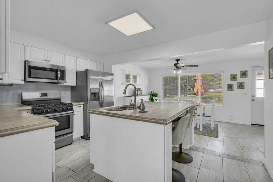 Bright kitchen and dining combo with island seating and backyard views — dinner and a show