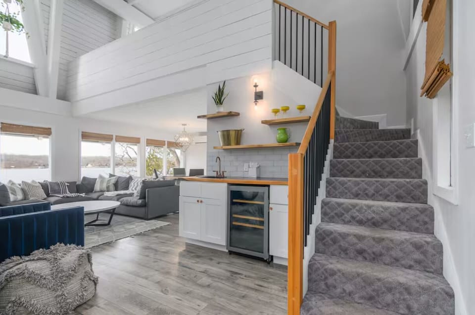 Bright and airy open-concept living with a cozy seating area, stylish mini kitchen, and convenient upstairs access—all with stunning lake views.