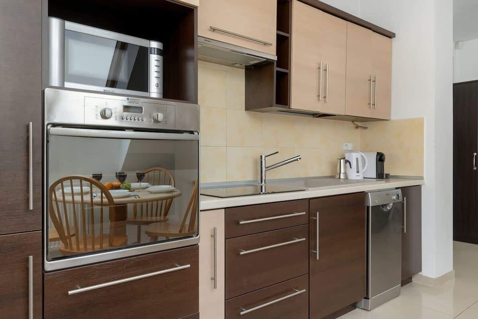 Modern kitchenette with dark cabinetry, dishwasher, induction hob, and elegant fittings.
