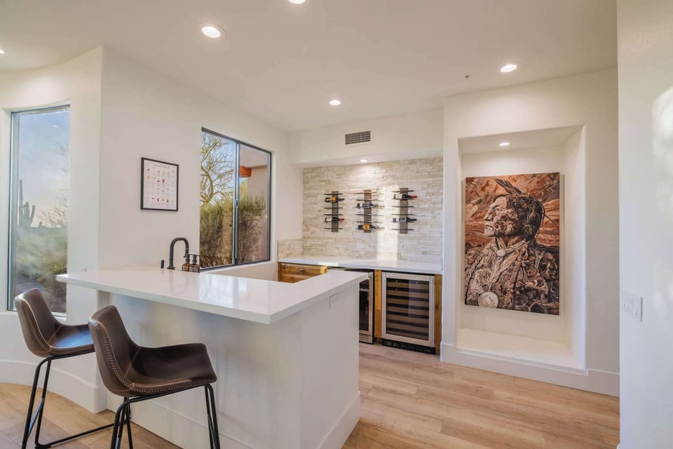 Sip and socialize at the modern wet bar, complete with a dual-zone wine fridge, wall-mounted racks, and a striking art feature created by Nate Laybourn for a luxurious touch.