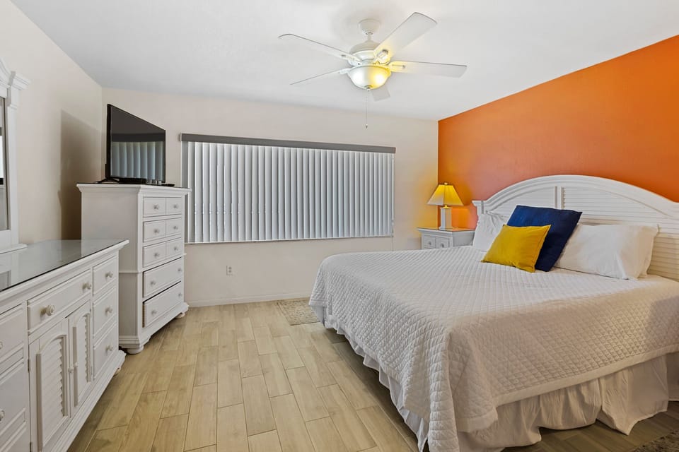 Unwind in this spacious master bedroom with a king bed, vibrant accent wall, and flat-screen TV. A perfect retreat for your beach stay, offering comfort and style after a day by the ocean.