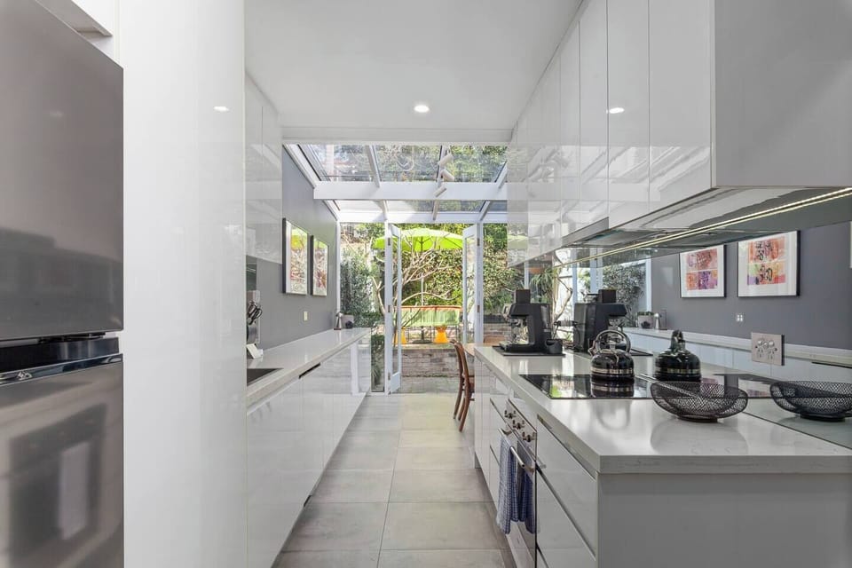Flowing to the dining space, the well-equipped kitchen includes an oven, espresso machine, and a dishwasher for easy cleanup.

