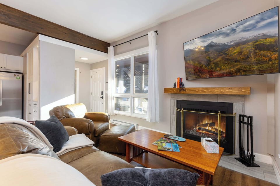 Living room with fireplace and large smart tv. Dining room and kitchen
