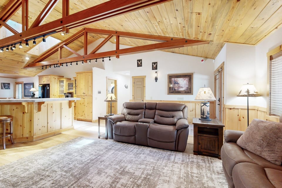 Cozy mountain living room with a stone fireplace, comfy seating, and smart TV—perfect for relaxing evenings, movie nights, and warm cabin vibes after outdoor adventures.