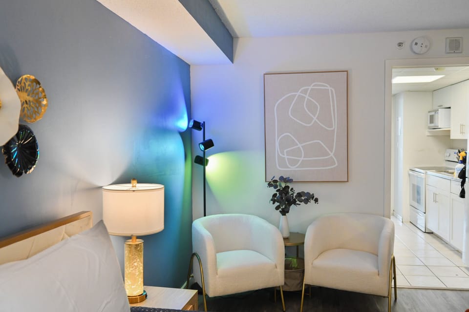 Chic bedroom offering queen bed, TV, and two relaxing single sofas.