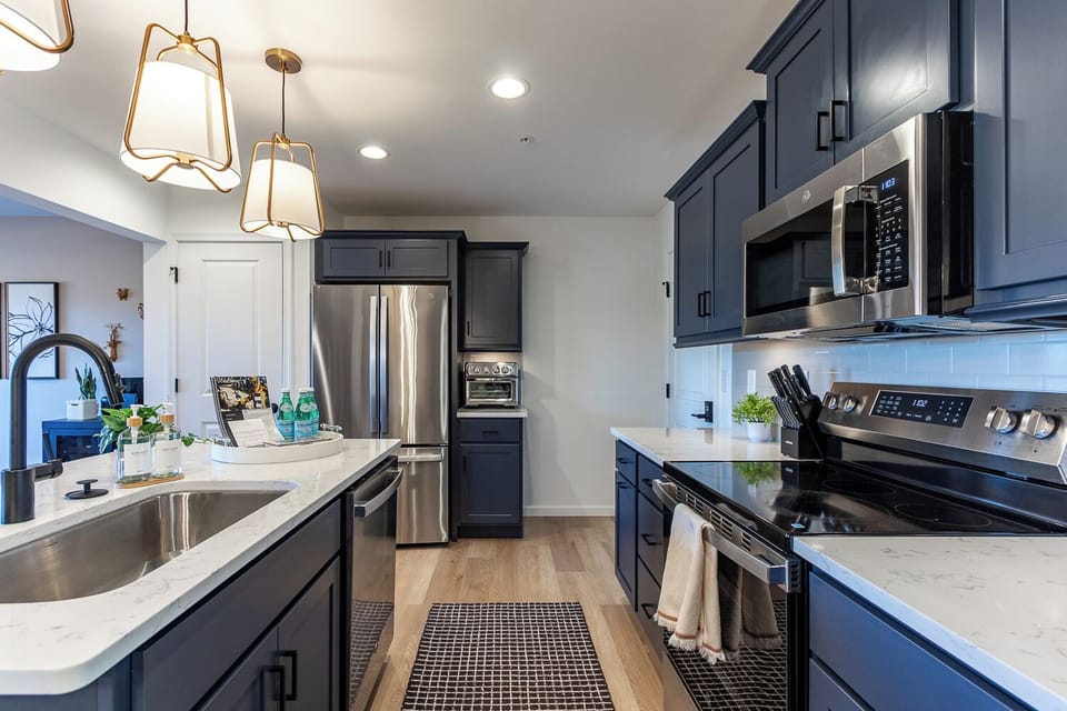 This spacious kitchen has everything you need, including a large size fridge, microwave, oven, four-burner range, oversized deep basin sink, coffee bar, blender, air fryer/toaster, and more!