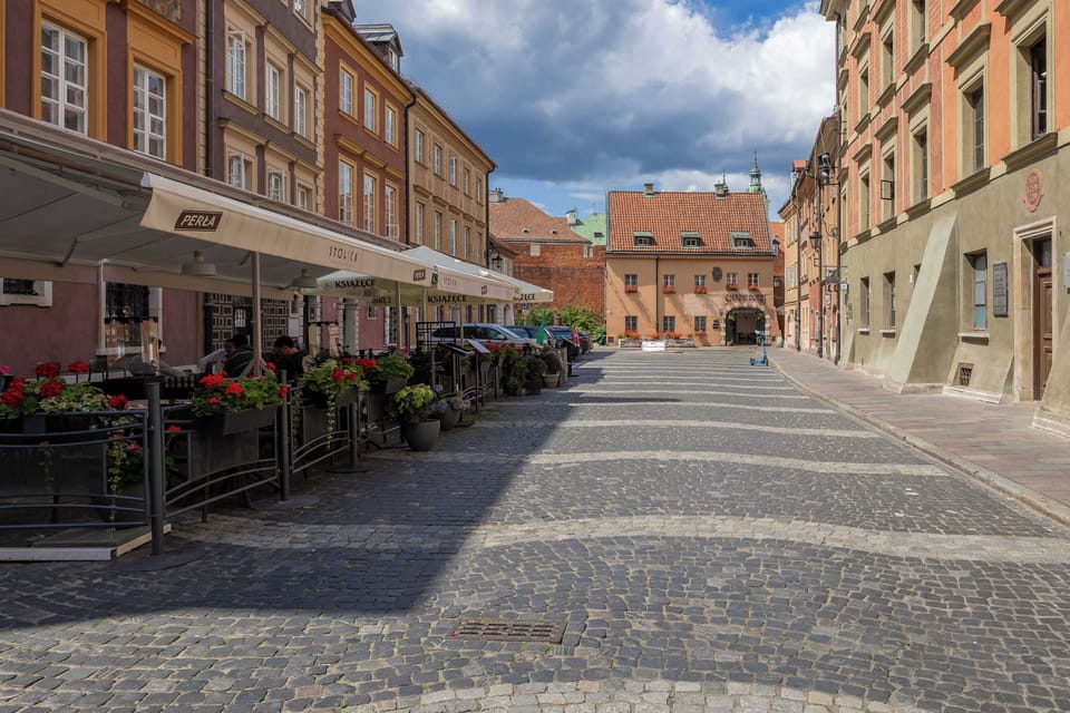 A picturesque cobblestone street lined with elegant historic buildings and charming outdoor cafés, creating a warm and inviting ambiance.
