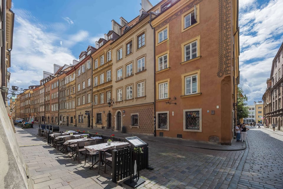 A picturesque cobblestone street lined with elegant historic buildings and charming outdoor cafés, creating a warm and inviting ambiance.