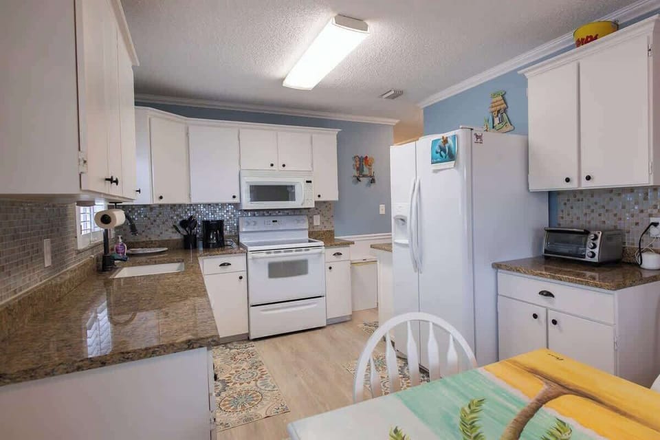 Cook up coastal meals in this modern kitchen featuring ample storage, updated appliances, and a seamless flow into the dining and living areas.