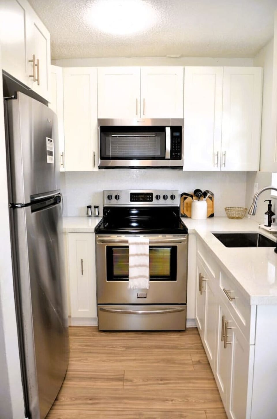 Fully equipped kitchen with stainless steel appliances, oven, and microwave perfect for home-cooked meals or reheating takeout.
