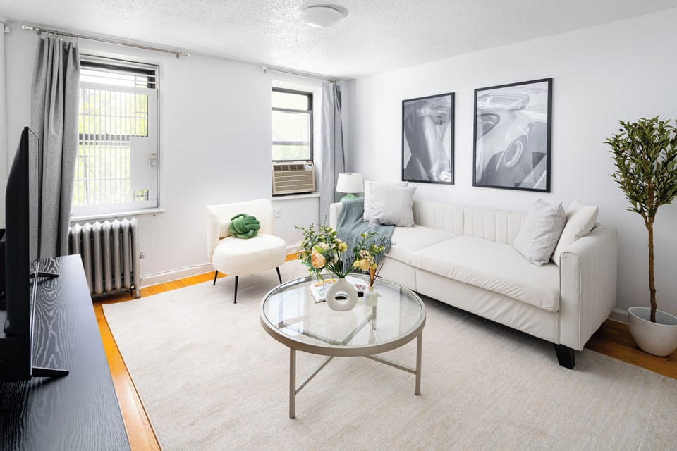 Sunny living room with sleek decor, cozy seating, and large windows