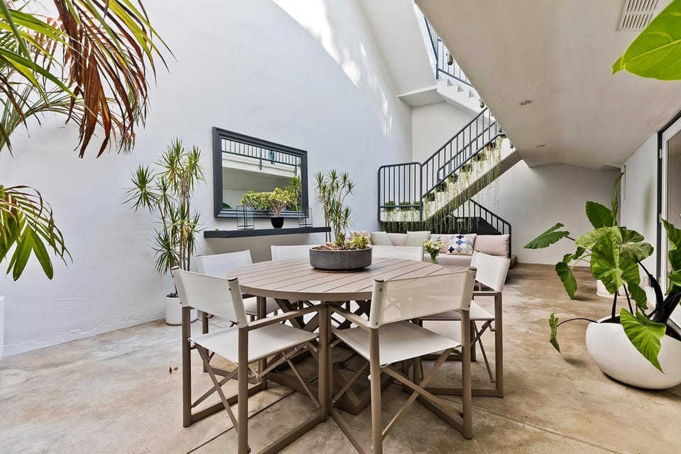 Peaceful atrium adjacent to kitchen with outdoor dining table, sofa and grill