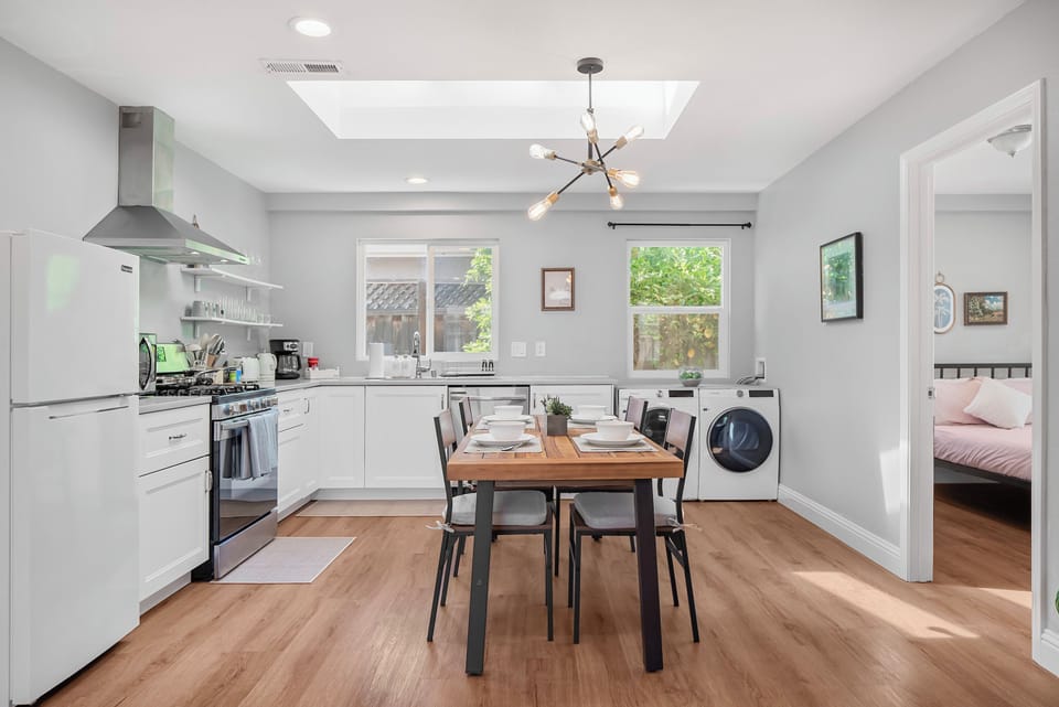 Bright kitchen with skylight, dining table, and washer-dryer combo next to the bedroom.