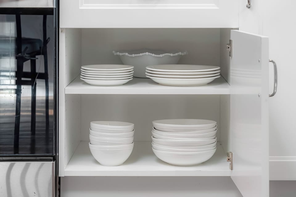 Full kitchen : Cabinet with neatly stacked plates, bowls, and glass storage containers.