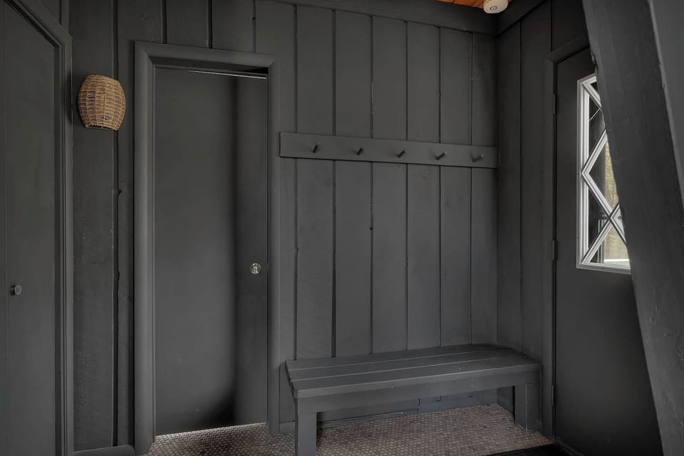 Stylish black-paneled entry invites you with hooks for gear and a welcoming bench!