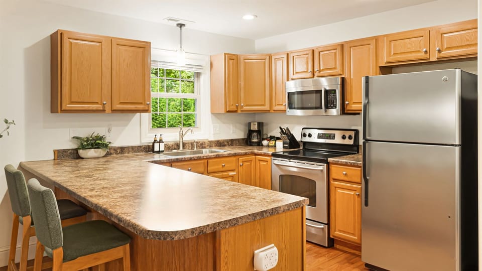 Cook for the group in a full kitchen: stainless steel appliances, prep island, and two bar seats for whoever wants to keep you company.