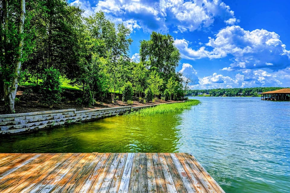 Waterfront - View from the dock looking back at the lush green lawn and stone seawall along the shoreline.